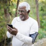 older man walking in woods looking at phone