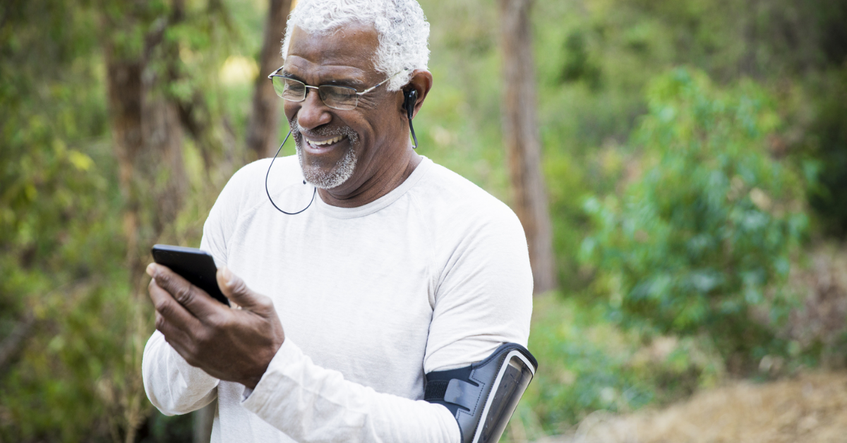 older man walking in woods looking at phone